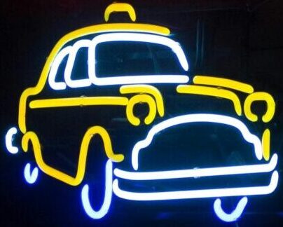 Bright neon sign depicting New York taxi glowing in the dark ambiance.